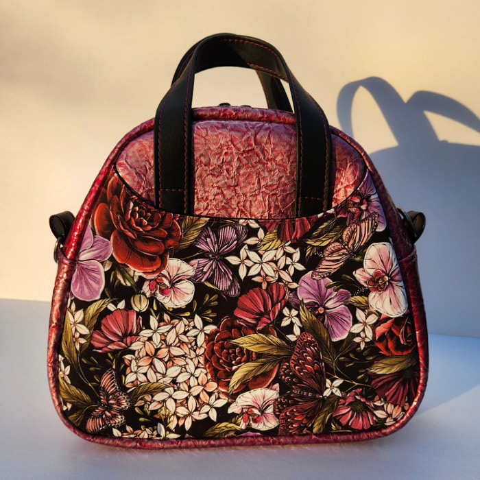 A finished handmade purse in patterned fabric with a leather base.
